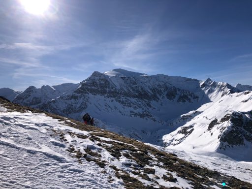 Schneebedeckte Berge und ein Wanderer unter einem klaren blauen Himmel.