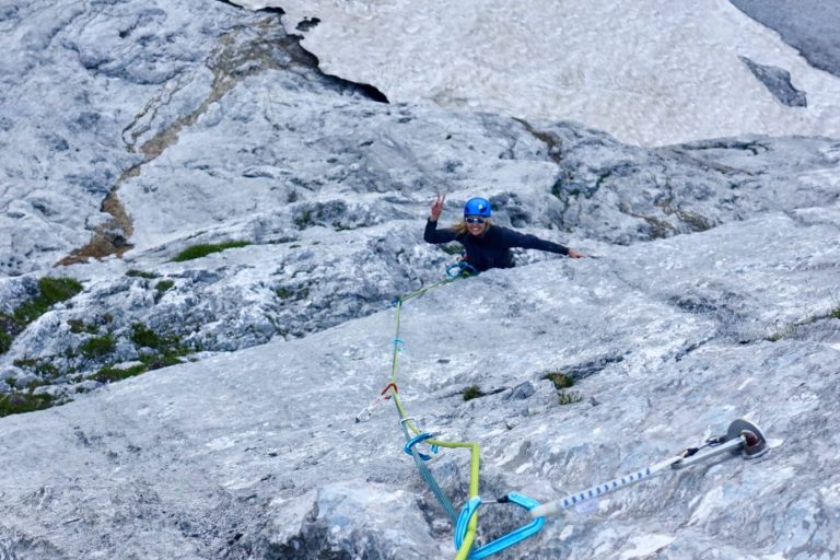 Kletterer, der an einer steilen Felswand mit Seil hochklettert.