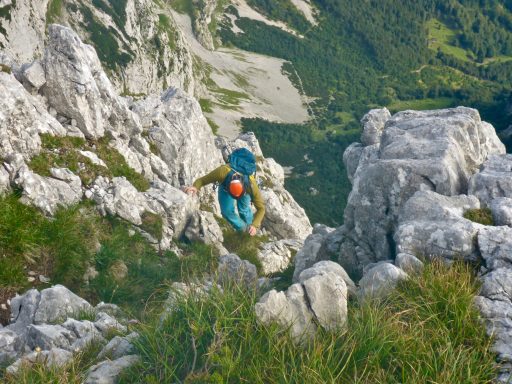 Bergsteiger klettert an steilen Felsen in einer bergigen Landschaft.