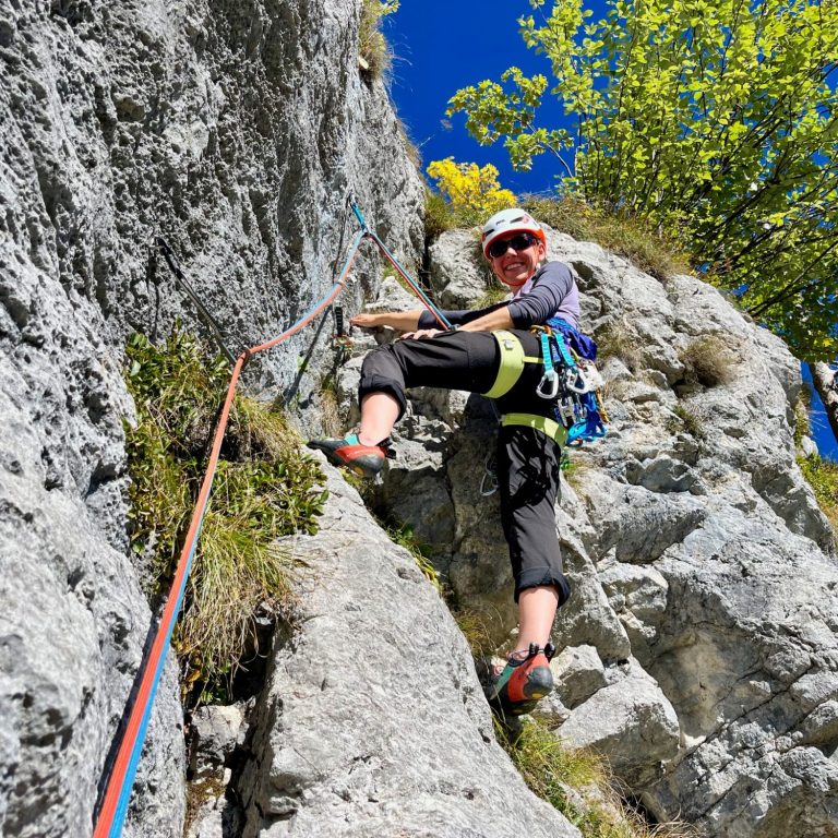 Gruppenkletterer an einer steilen Felswand mit Blick auf den Lago di Garda.