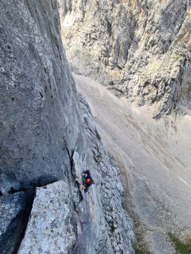 Kletterer an einer steilen Felswand mit Blick auf den Abgrund darunter.