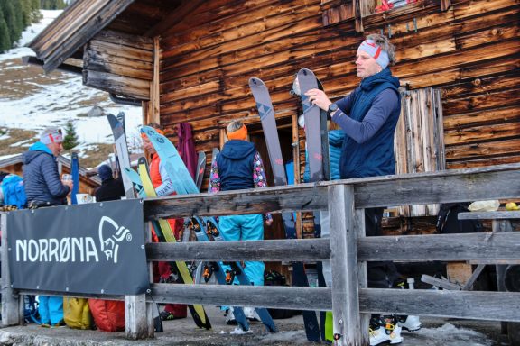 Skitouren Camp Rofan Personen stehen vor einer Hüttenfassade und halten Skier in der Hand.