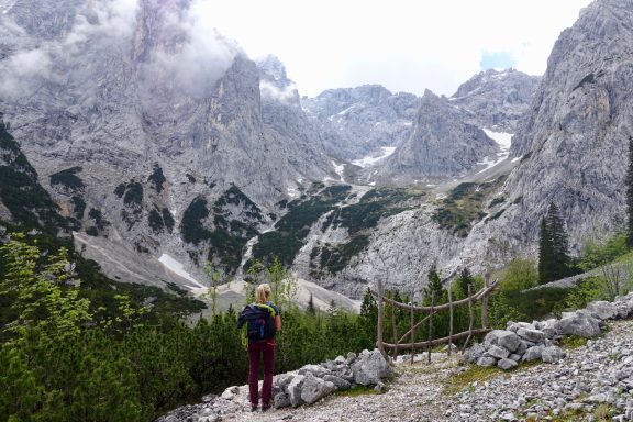 Wanderer im Gebirge mit dramatischer Berglandschaft und bewaldeten Hängen.