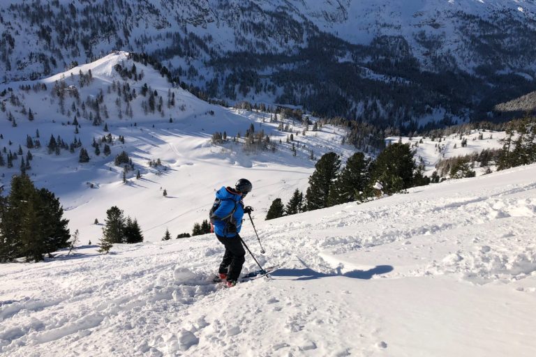 Skifahrer im Schnee mit Bergen im Hintergrund.
