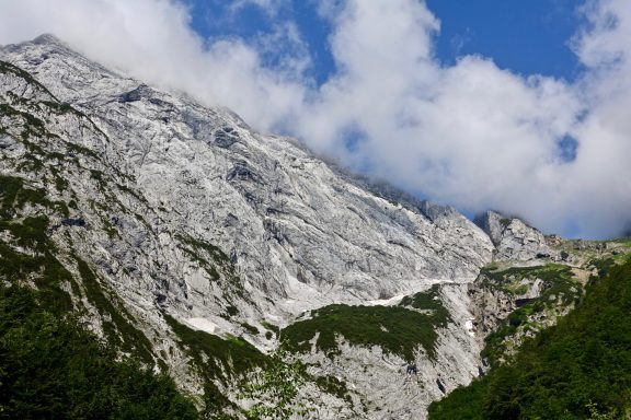 Felsige Berglandschaft unter blauem Himmel mit weißen Wolken.