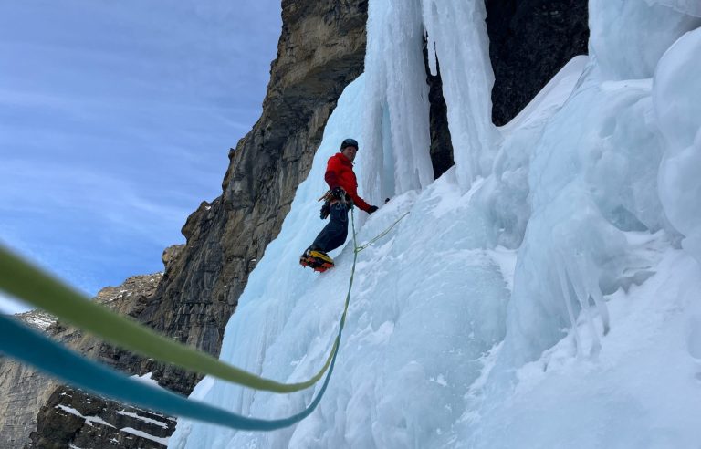 Ein Bergsteiger klettert an einer gefrorenen Wasserfallstruktur. 