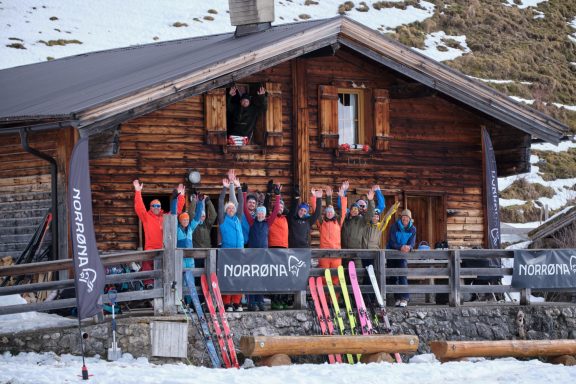 Skitouren Camp Rofan Gruppe von Skifahrern vor einer Almhütte, freudig mit Händen in der Luft.