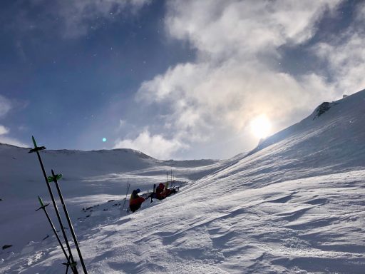Skifahrer unterwegs auf einem schneebedeckten Hang bei sonnigem Wetter.