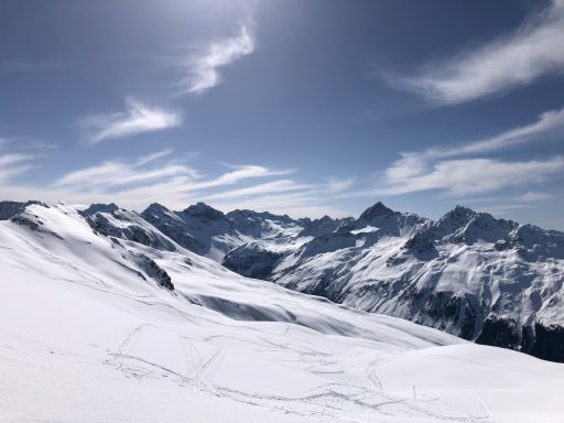 Schneebedeckte Berge unter klarem Himmel mit einigen Wolken.