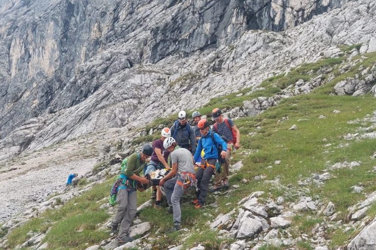 Menschen gruppieren sich am Hang eines Berges, offenbar bei einer Kletterübung.