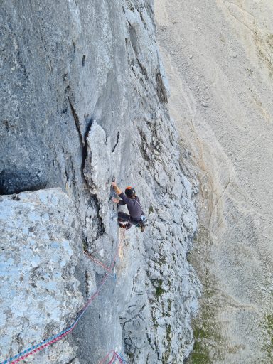 Kletterer an einer steilen Felswand mit Seil und Sicherung.