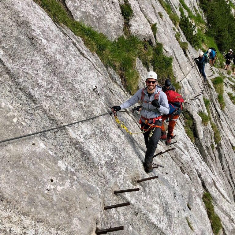 Bergsteiger nutzen eine Drahtseilsicherung auf steilem Felsen.