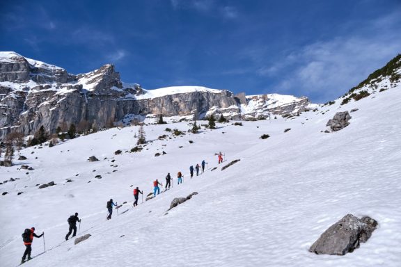 Skitouren Camp Rofan Skifahrer wandern in einer verschneiten Berglandschaft unter blauem Himmel.
