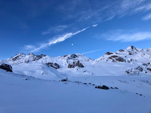 Schneebedeckte Berge unter einem klaren blauen Himmel mit einigen Wolken.