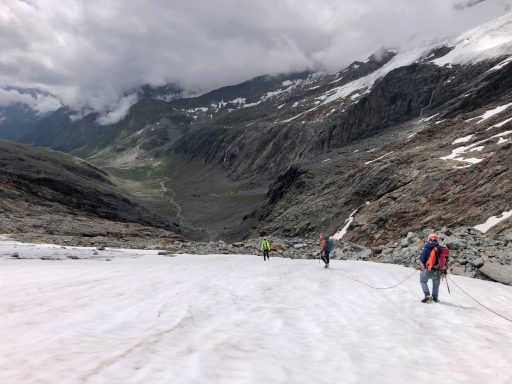 Menschen wandern auf einem schneebedeckten Hang in den Bergen.