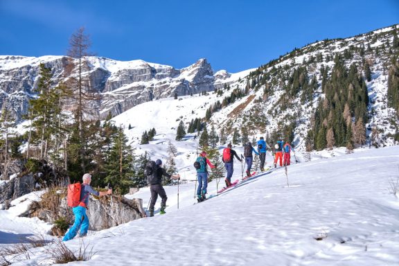 Skitouren Camp Rofan Gruppe von Skifahrern in schneebedeckter Landschaft mit Bergen im Hintergrund.