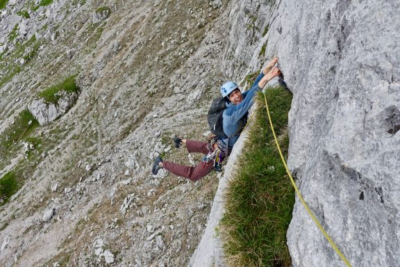 Kletterer, der an einer steilen Felsenwand mit Seil und Sicherheitsausrüstung klettert.
