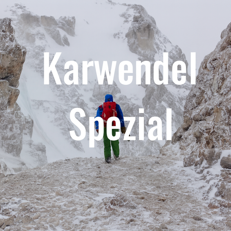 Eine Person wandert in schneebedeckter Gebirgslandschaft.