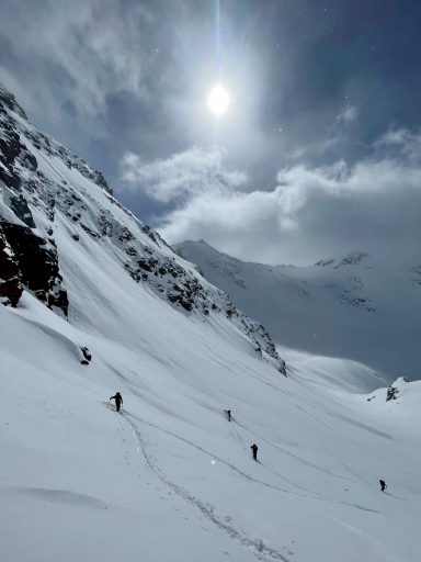 Schneebedeckte Berge mit Wanderern und strahlendem Himmel.