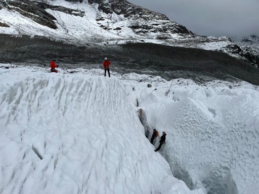 Zwei Bergsteiger auf einer verschneiten Anhöhe in der Nähe eines Gletschers.