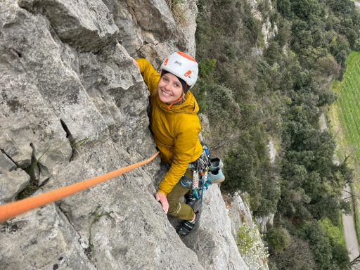 Kletterer in gelber Jacke, der eine steile Felswand erklimmt.